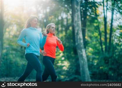 Two Women Jogging Outdoors in Public Park in the Fall.. Two Women Jogging Outdoors in a Park in the Fall.