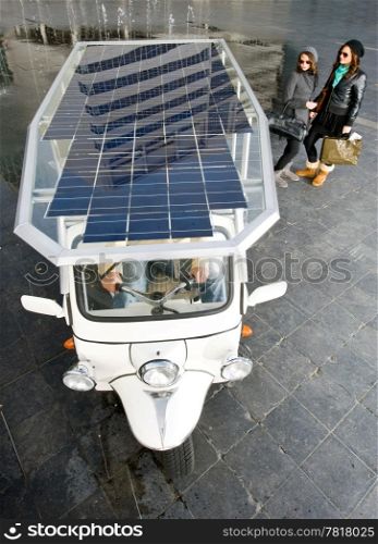 Two women looking at a solar powered tuc tuc waiting for its next fare