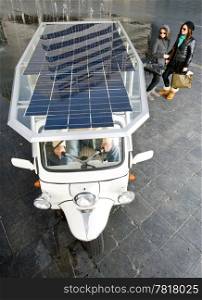 Two women looking at a solar powered tuc tuc waiting for its next fare