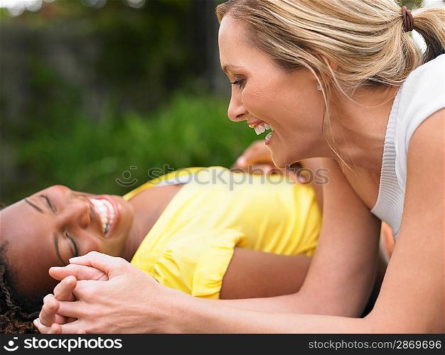 Two women lying down and laughing side view