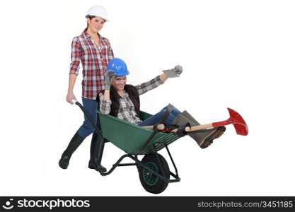 Two women messing around wuth wheelbarrow