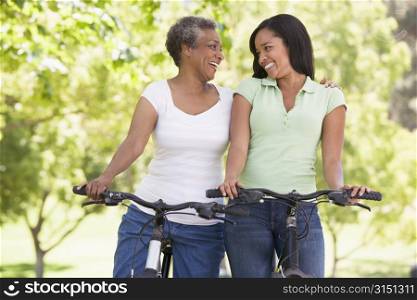 Two women on bikes outdoors smiling