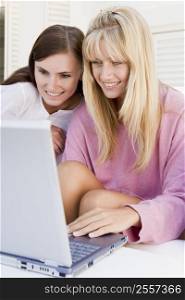 Two women on patio using laptop smiling