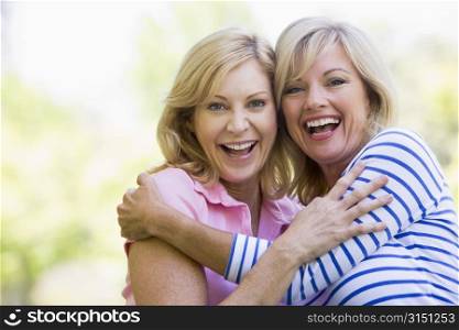 Two women outdoors hugging and smiling