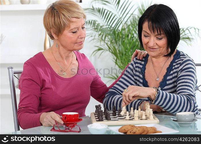 Two women playing chess and having a chat