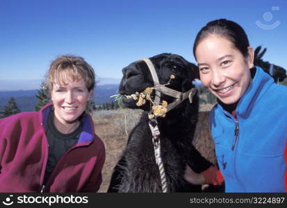 Two Women Posing With Their Pack Llama