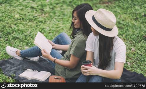 Two women reading book together while sitting in the woods
