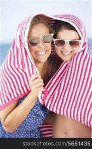 Two Women Sheltering From Sun On Beach Holiday