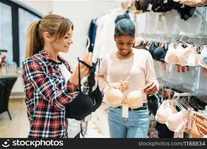 Two women shopping, lingerie department. Shopaholics in clothing store, consumerism lifestyle, fashion, female shoppers in underwear section