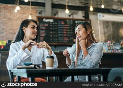 Two women sitting and drinking coffee and chatting in a cafe