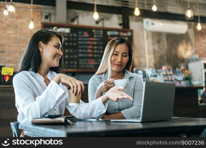 Two women sitting and working with a laptop in a coffee shop