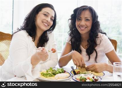 Two women sitting at dinner table smiling (high key)