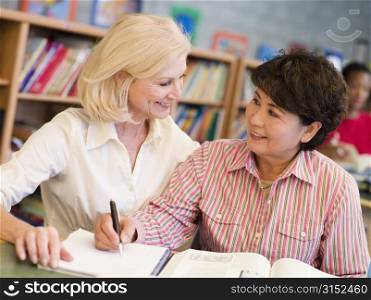 Two women sitting in library with a book and notepad (selective focus)