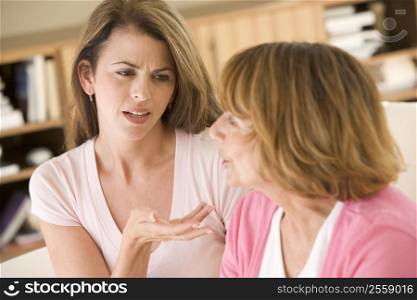 Two women sitting in living room arguing