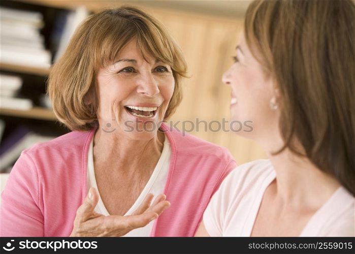 Two women sitting in living room talking and smiling
