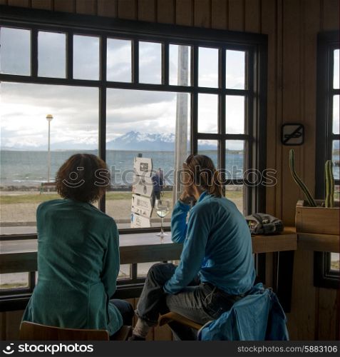 Two women sitting on chairs looking at a view, Puerto Natales, Patagonia, Chile