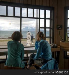 Two women sitting on chairs looking at a view, Puerto Natales, Patagonia, Chile