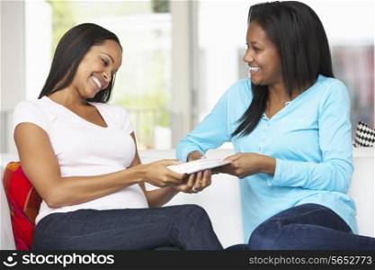 Two Women Sitting On Sofa Exchanging Gifts