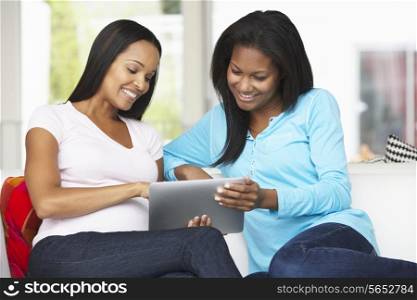 Two Women Sitting On Sofa With Tablet Computer