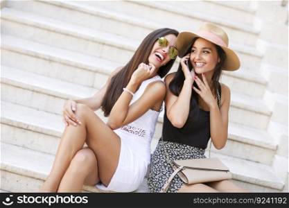 Two women sitting on the stairs outside