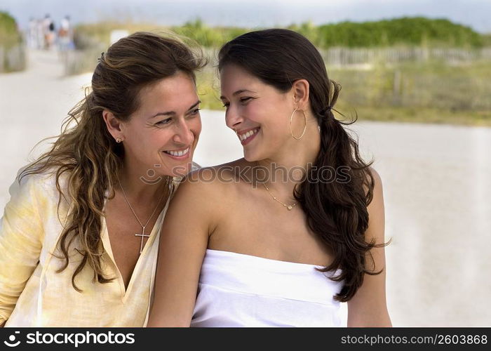 Two women sitting side by side at beach