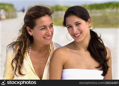 Two women sitting side by side at beach