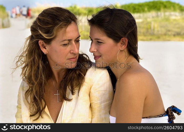 Two women sitting side by side at beach