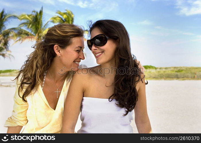 Two women sitting side by side at beach