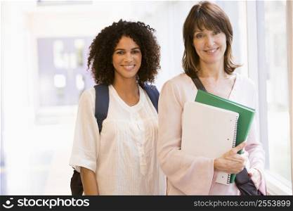 Two women standing in corridor with books (high key)