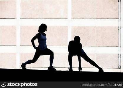 Two women stretching before running.