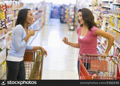 Two women talking to each other at a grocery store