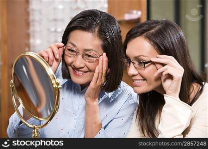 Two women trying on eyeglasses in store
