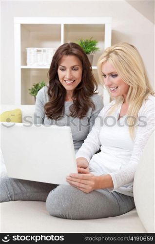 Two Women Using Laptop Computer At Home on Sofa