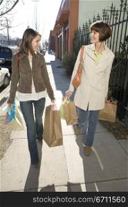 Two women walking holding bags