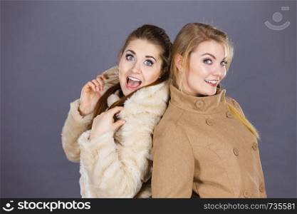 Two women, wearing light brown coat and furry jacket. Winter fashion concept.. Two women wearing light brown coats