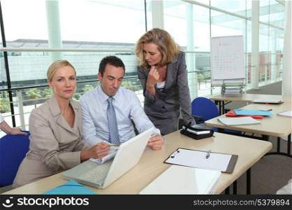 two women wearing suits and a man are working in a company