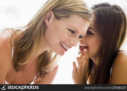 Two women whispering and smiling