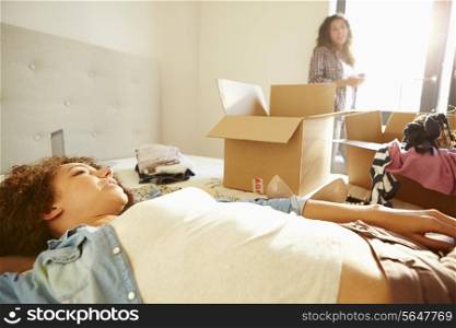Two Women With Boxes In Bedroom Moving Into New Home