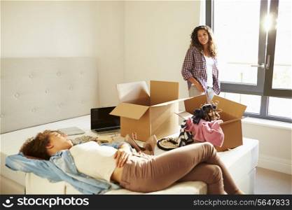 Two Women With Boxes In Bedroom Moving Into New Home