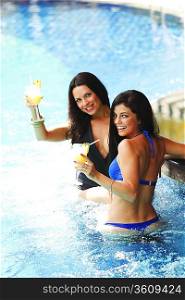 Two women with cocktails in swimming pool