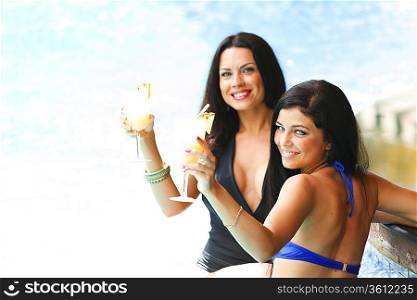 Two women with cocktails in swimming pool