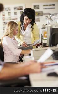 Two Women Working At Desks In Busy Creative Office