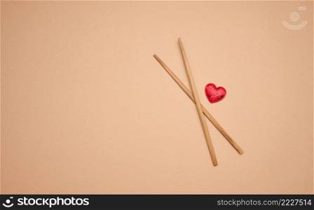 two wooden chopsticks on a brown background, copy space, top view