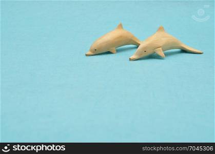 Two wooden dolphin figurines isolated on a blue background
