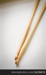 Two wooden drum sticks from above on a pale background