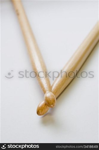 Two wooden drum sticks from above on a pale background