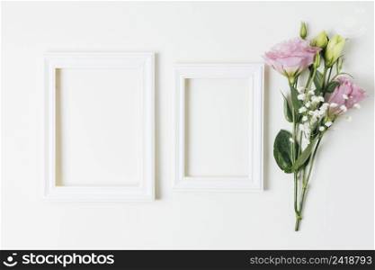 two wooden empty frames near pink eustoma baby s breath flowers white background