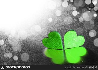 Two wooden hearts. Two green wooden hearts on metal background with bokeh lights