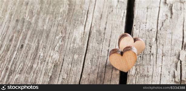 Two wooden hearts. Two small wooden hearts on old cracked wood background