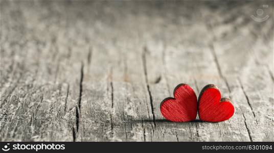 Two wooden hearts. Two small wooden red hearts on old cracked wood background